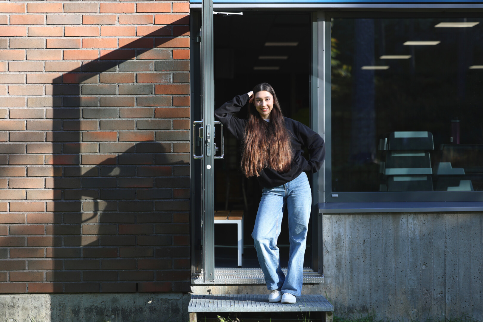 Young woman leaning against an open door outside