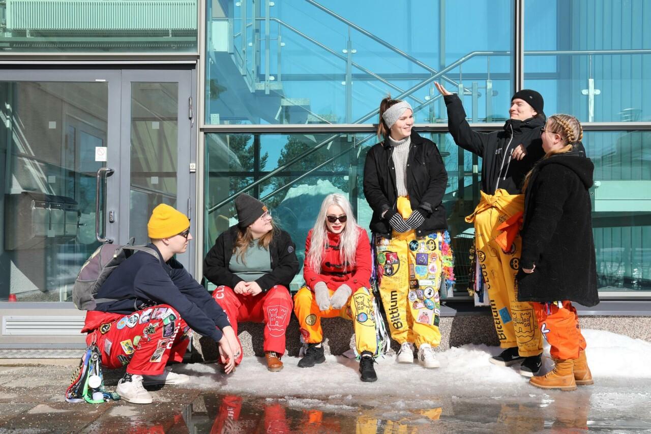 six students gathered to chat in front of the building's glass wall