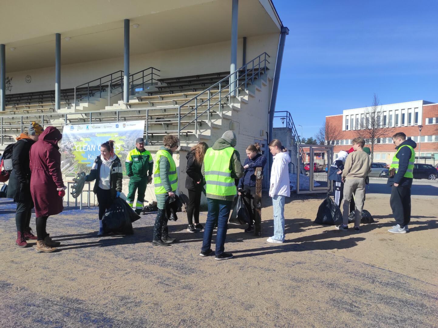 People in the sports field in front of the stand during the SUSWAM Clean Games -event on a sunny day. Picture: Ella Lukkari / Kajaani University of Applied Sciences.