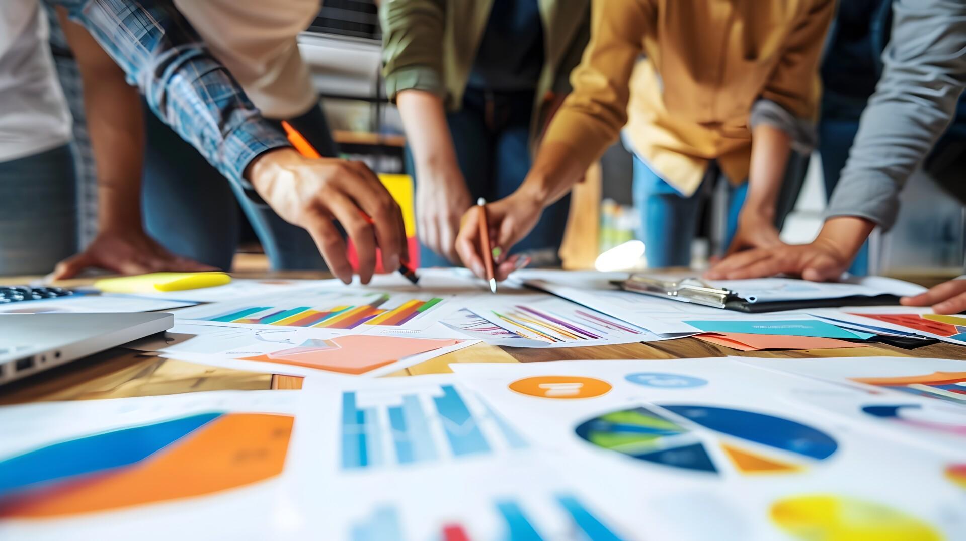 A group of people gathered around a table, analyzing printed reports and graphs. Picture: pkproject / Adobe Stock