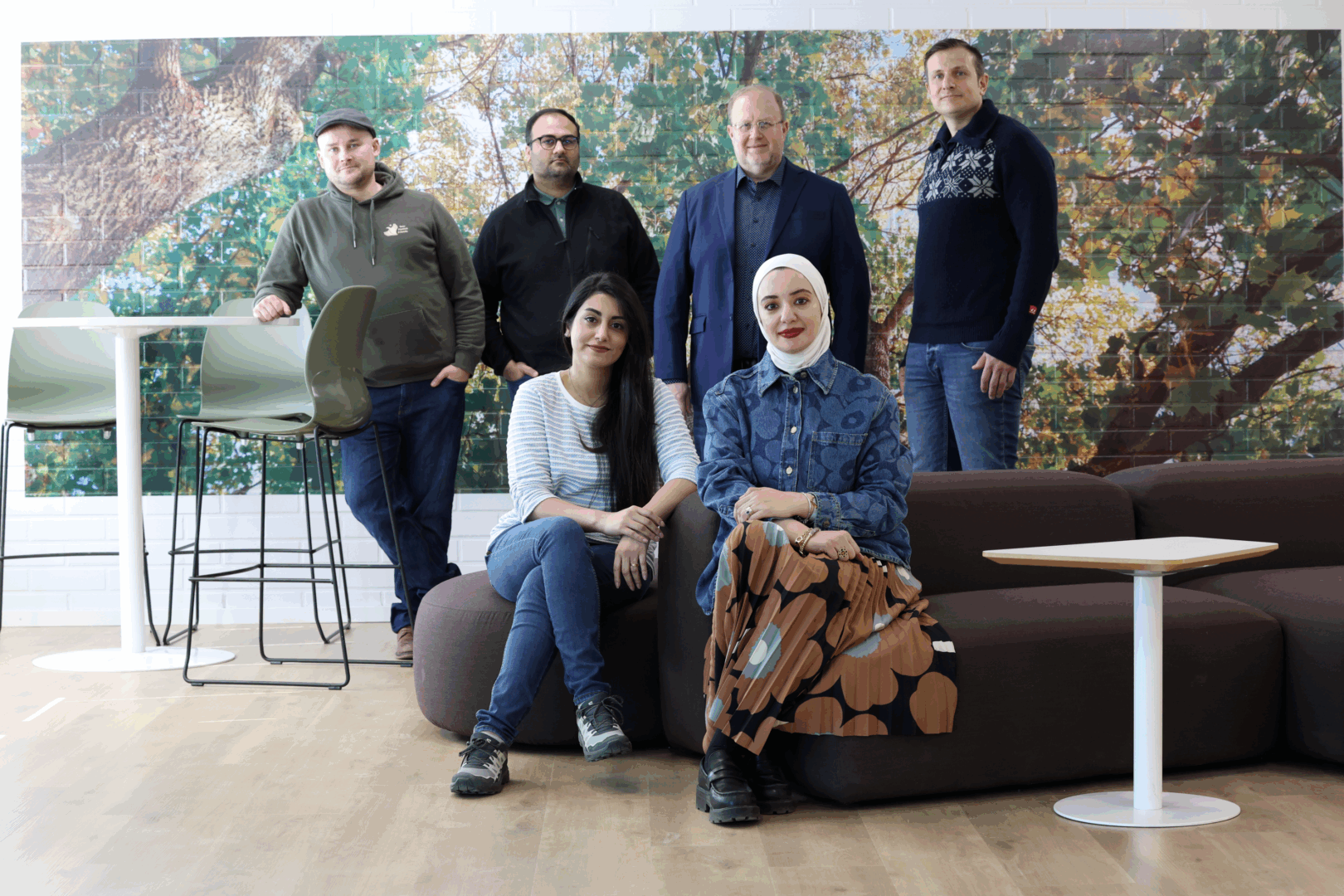 Kajaani University of Applied Sciences' Data Nexus Solutions research group's picture 2025. The research group is in a lobby at KAMK, some of are standing, some of them are sitting on a sofa. Picture: KAMK.