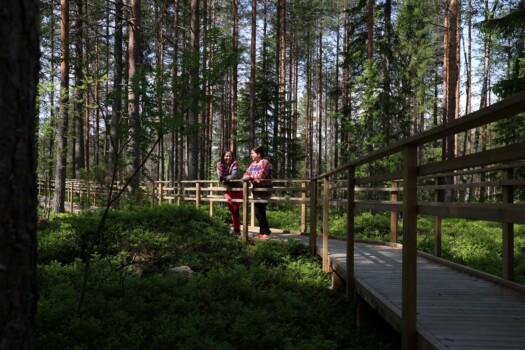 Two people standing in Kajaani's Health Forest route on a summer day.
